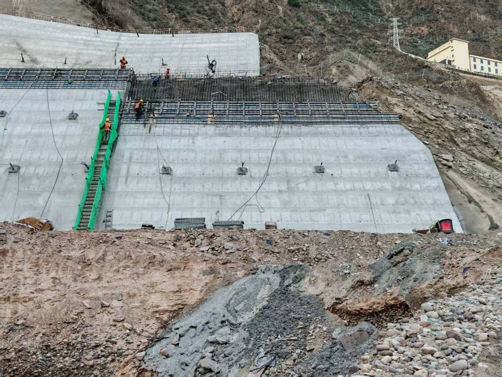 Concrete slope facing under construction, with exposed reinforcement above the cast sections